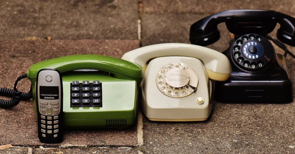 A variety of antique, vintage, and modern telephones displayed on pavement.